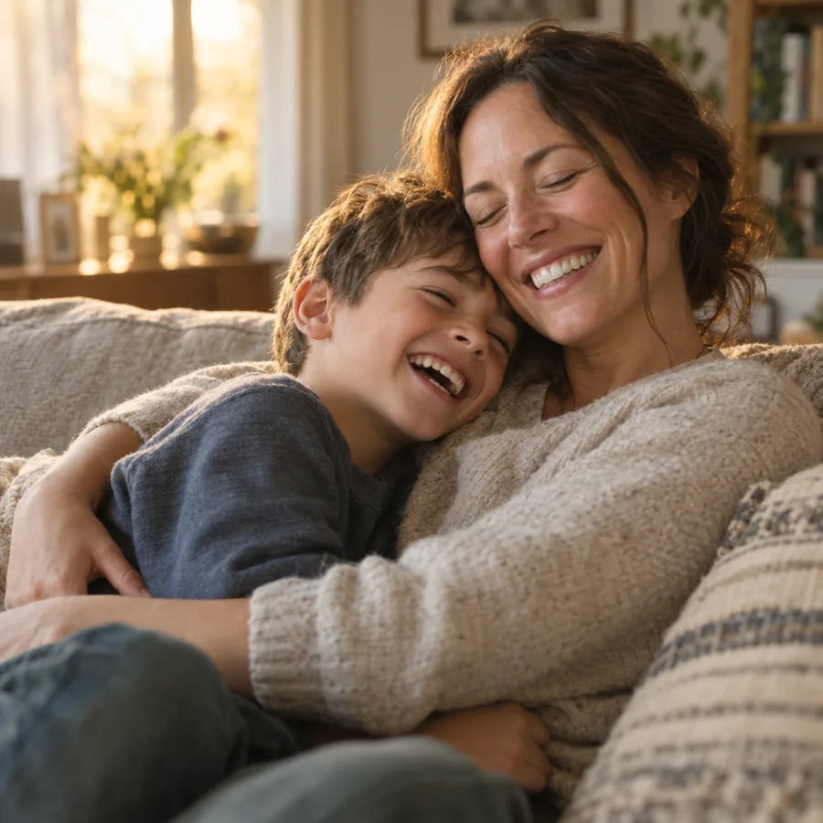 A laughing boy hugging his mom on the sofa